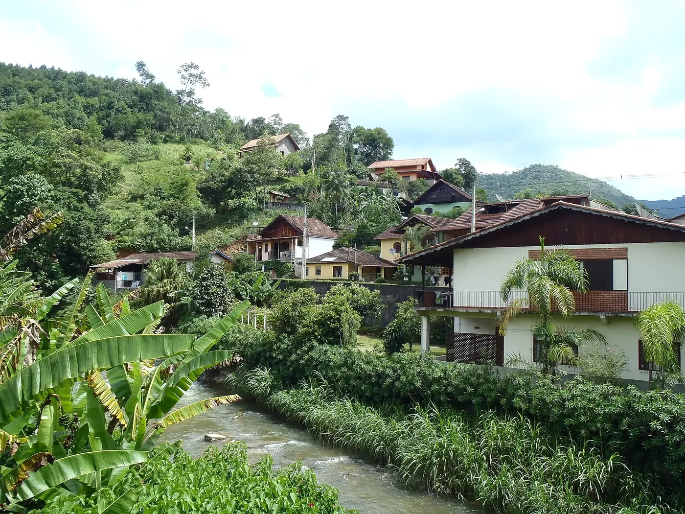Rio cortando a vila de Lumiar entre casas e bananeiras