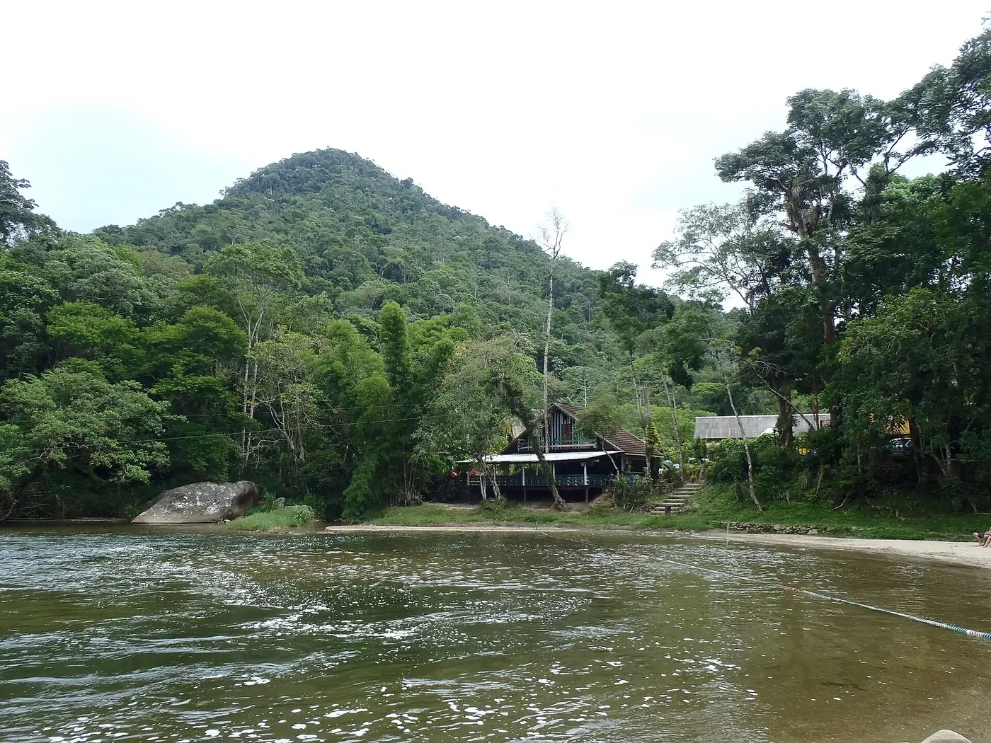 Trecho largo e calmo de rio em Lumiar com mata ao redor