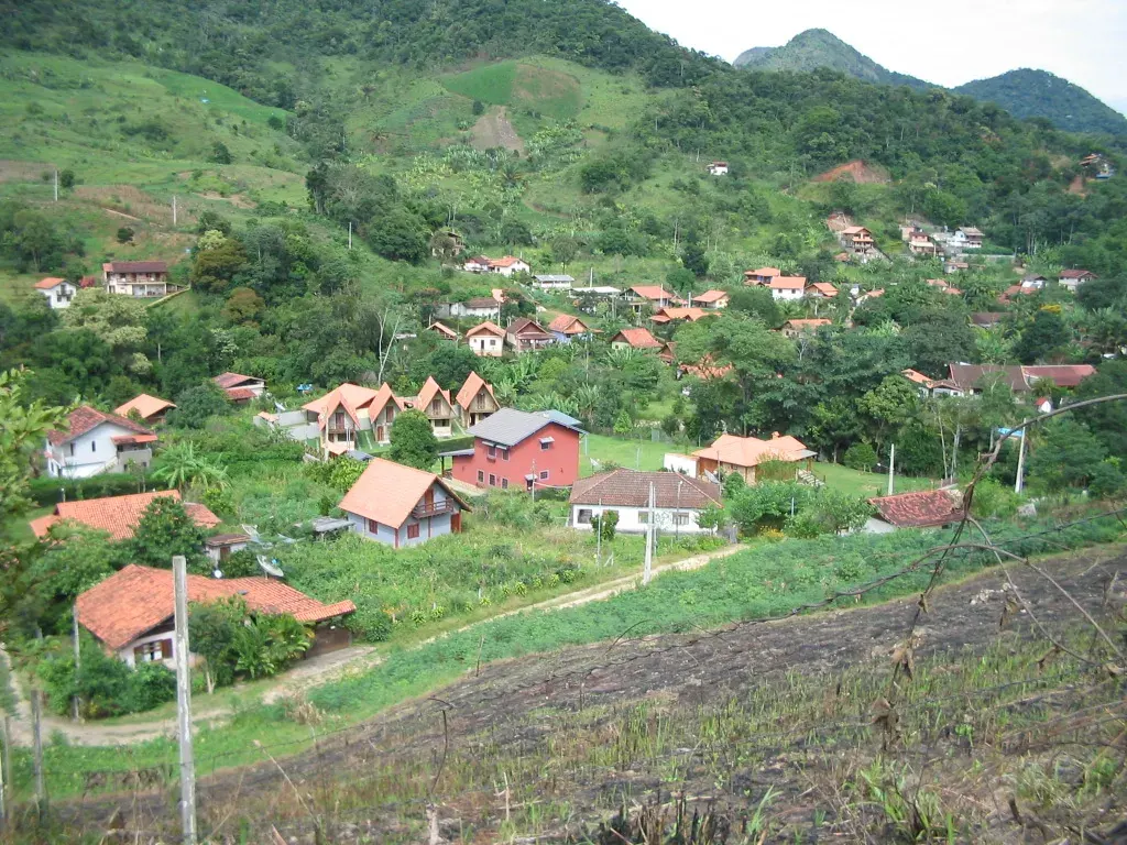 Vista do vale de Lumiar com casas de telhado vermelho entre morros de Mata Atlântica